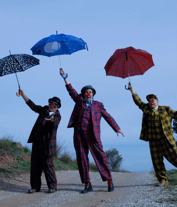 Tres pallasos amb paraigues saltant a un camí (de Remember show)